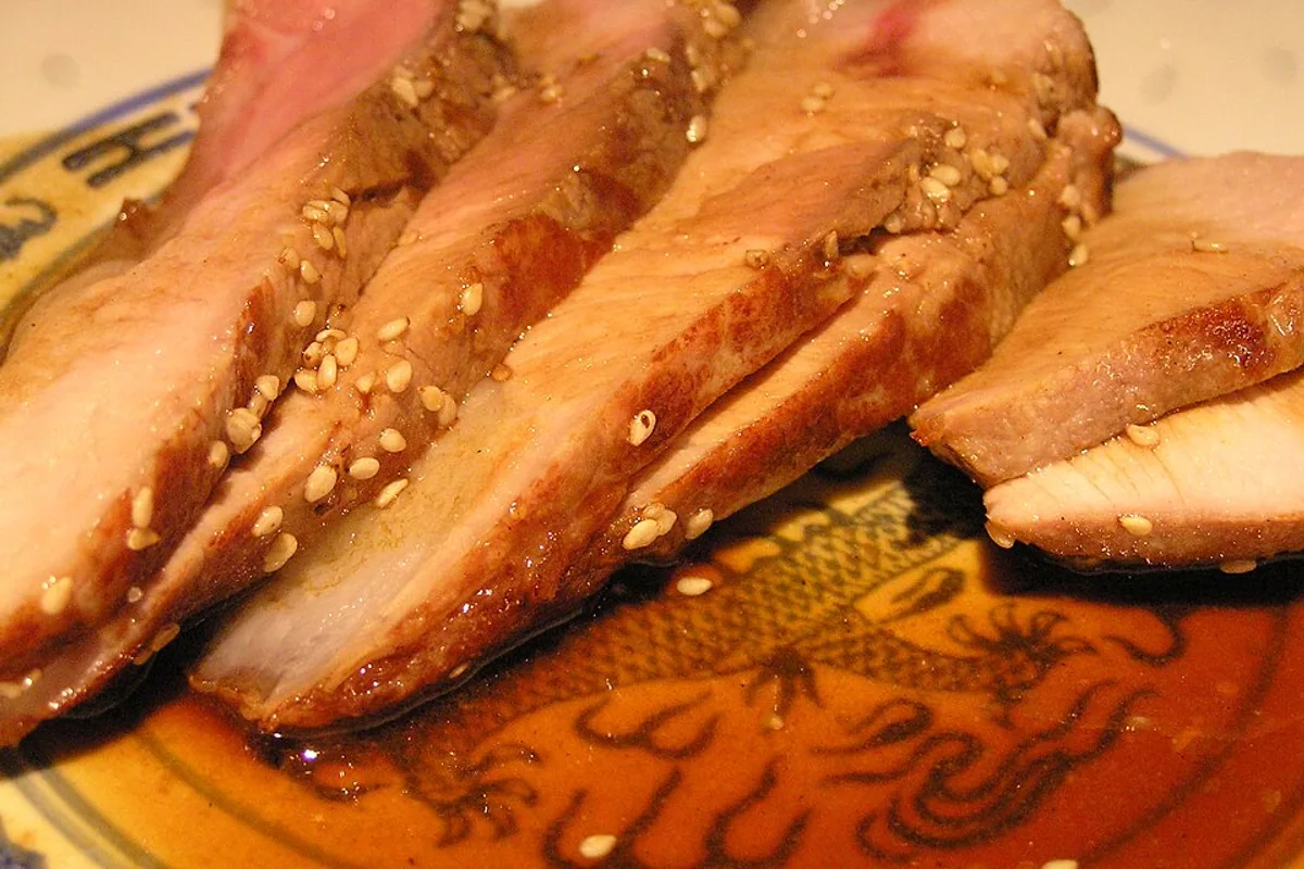 Sliced pork sirloin chops in glossy cider pan sauce with sesame seeds