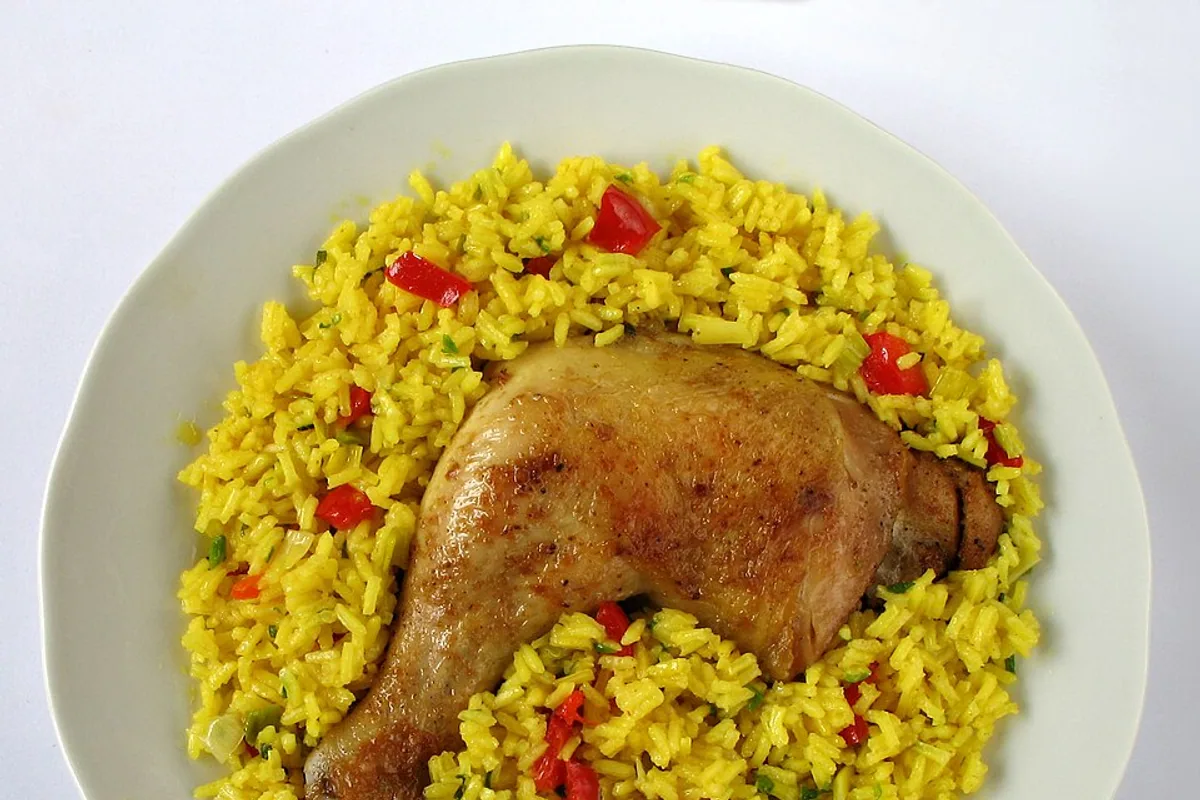 Arroz con pollo with a browned chicken thigh yellow rice peas and red pepper
