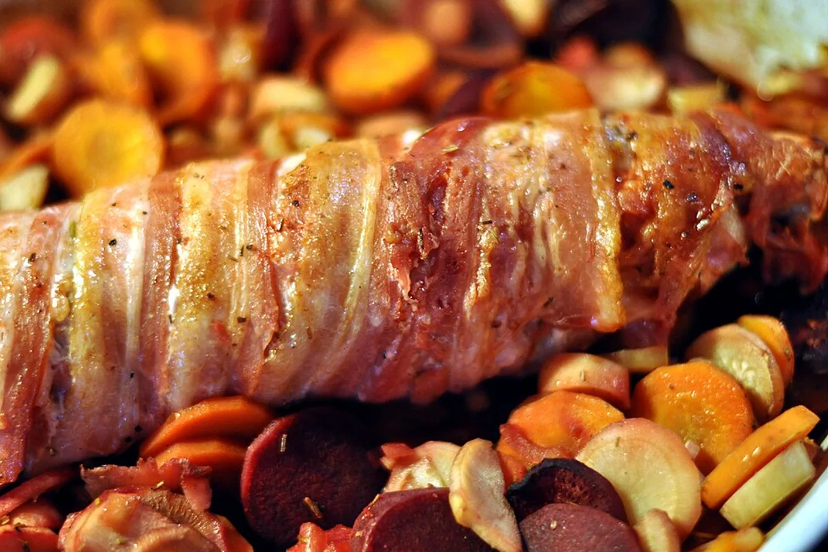 Bacon-wrapped pork tenderloin roasted with potatoes carrots and parsnips