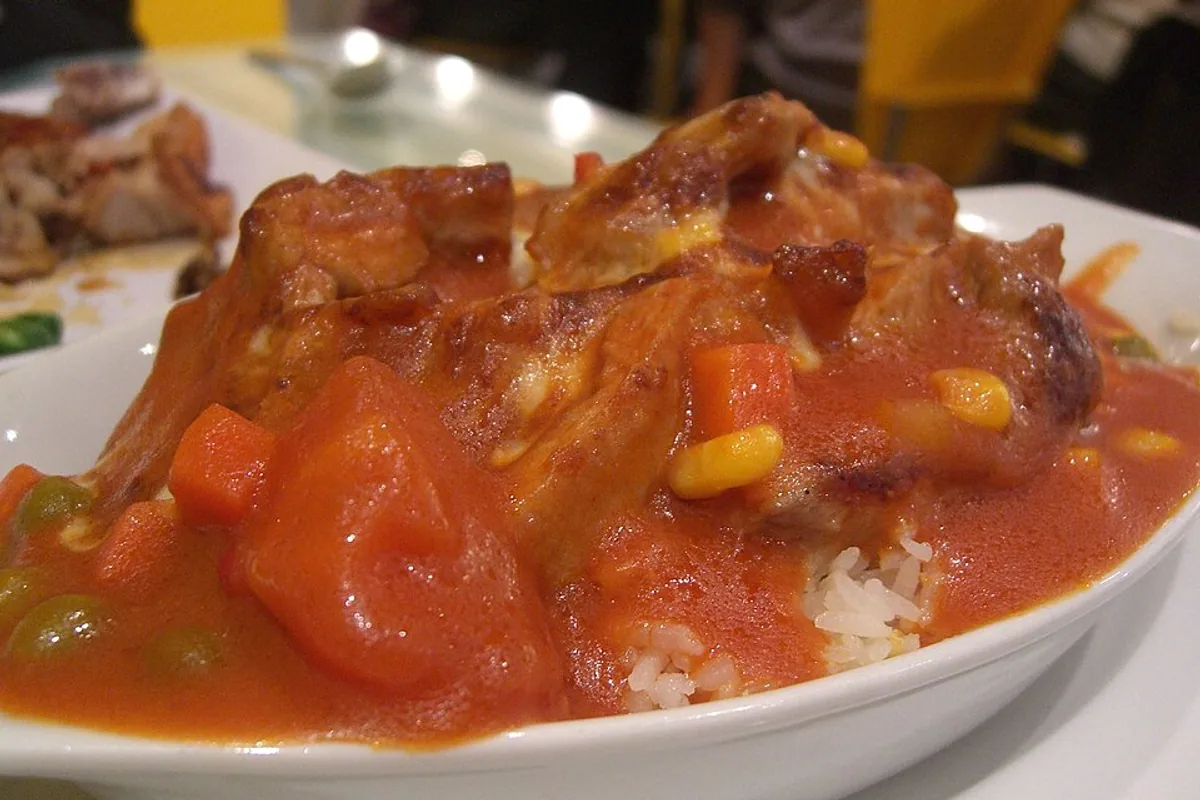 Baked pork chop in tomato sauce with corn peppers and white rice