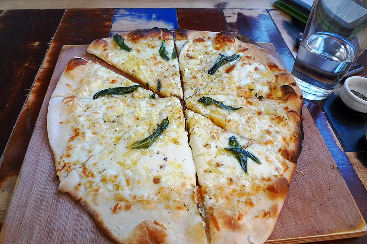 Sliced white pizza with ricotta mozzarella basil and browned crust