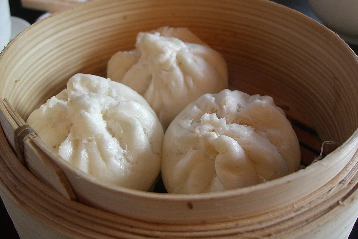 Steamed BBQ pork bao buns in a bamboo basket