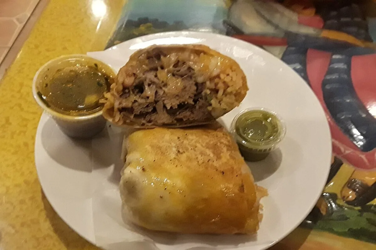 Cut beef birria burrito with green and chile dipping sauces