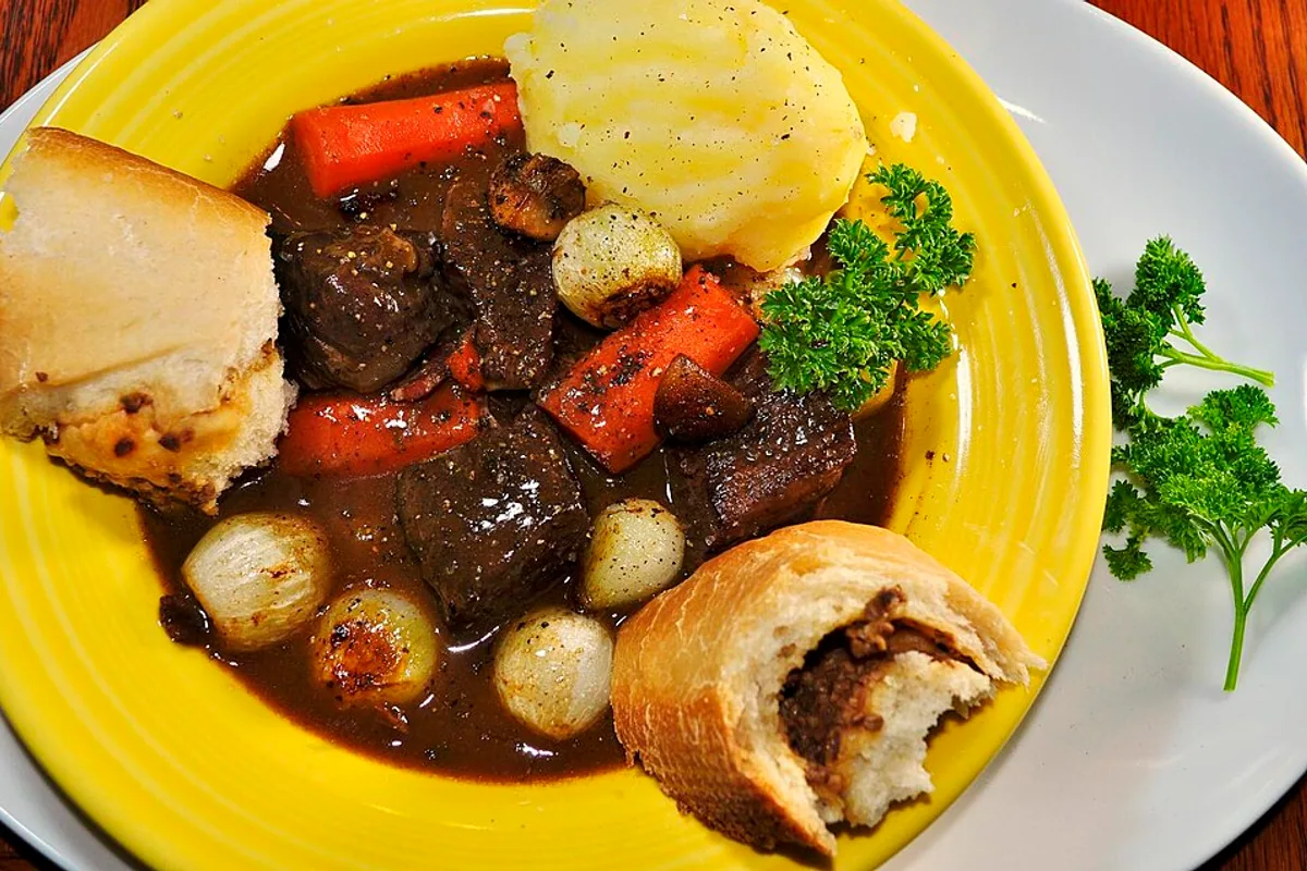 Beef bourguignon with mushrooms pearl onions carrots dark sauce and mashed potatoes