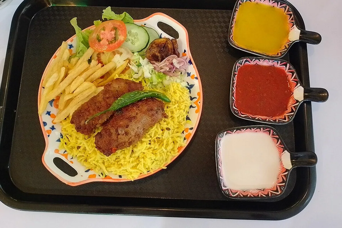 Beef kebab plate with basmati rice fries chopped salad yogurt and tomato sauces