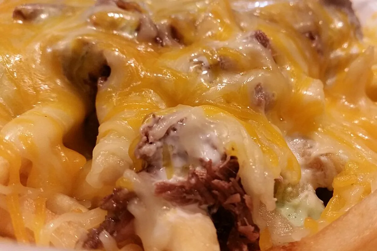 Close-up of beef lengua loaded fries with melted cheese and sauce