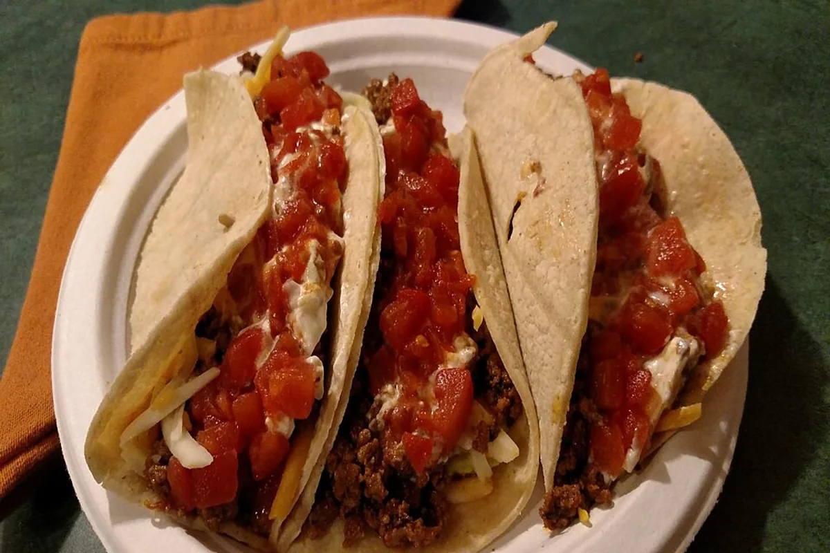 Ground beef tacos with shredded cheddar chopped tomato and sour cream
