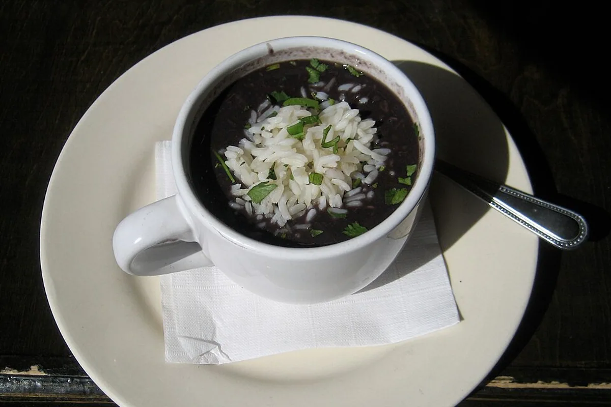 Cup of thick black bean soup with a white garnish
