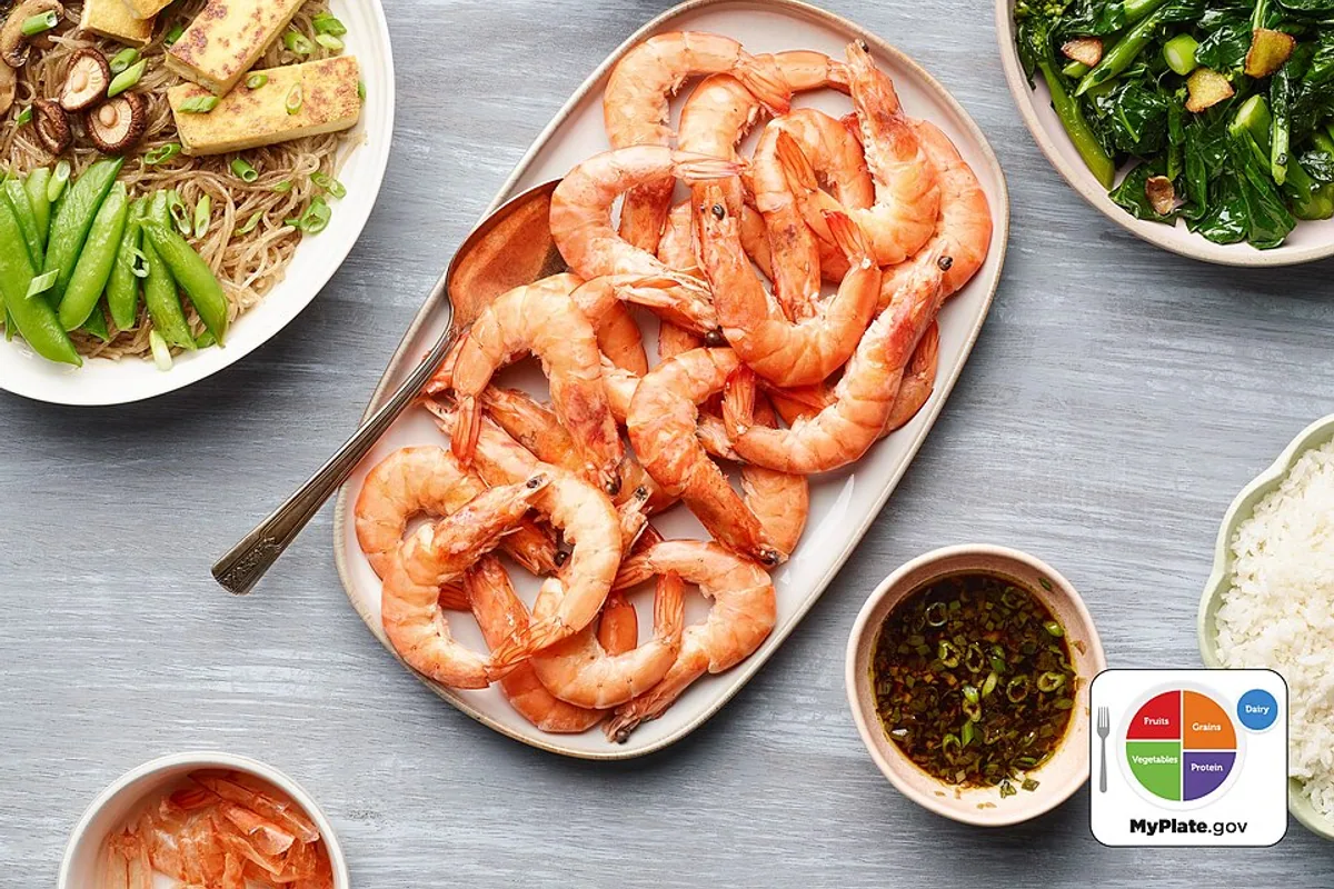 Shell-on boiled shrimp platter with tomato slices lettuce and dipping sauce