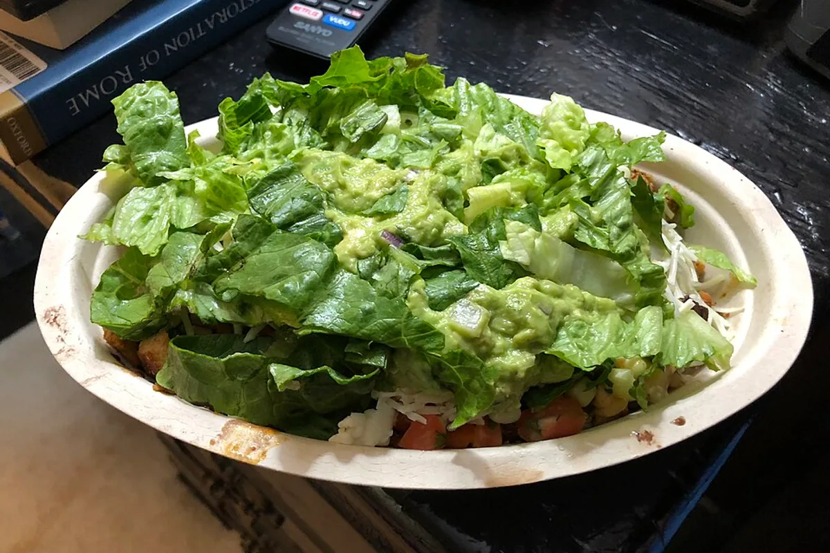 Chicken and black bean burrito bowl with brown rice lettuce pico cheese sour cream and guacamole