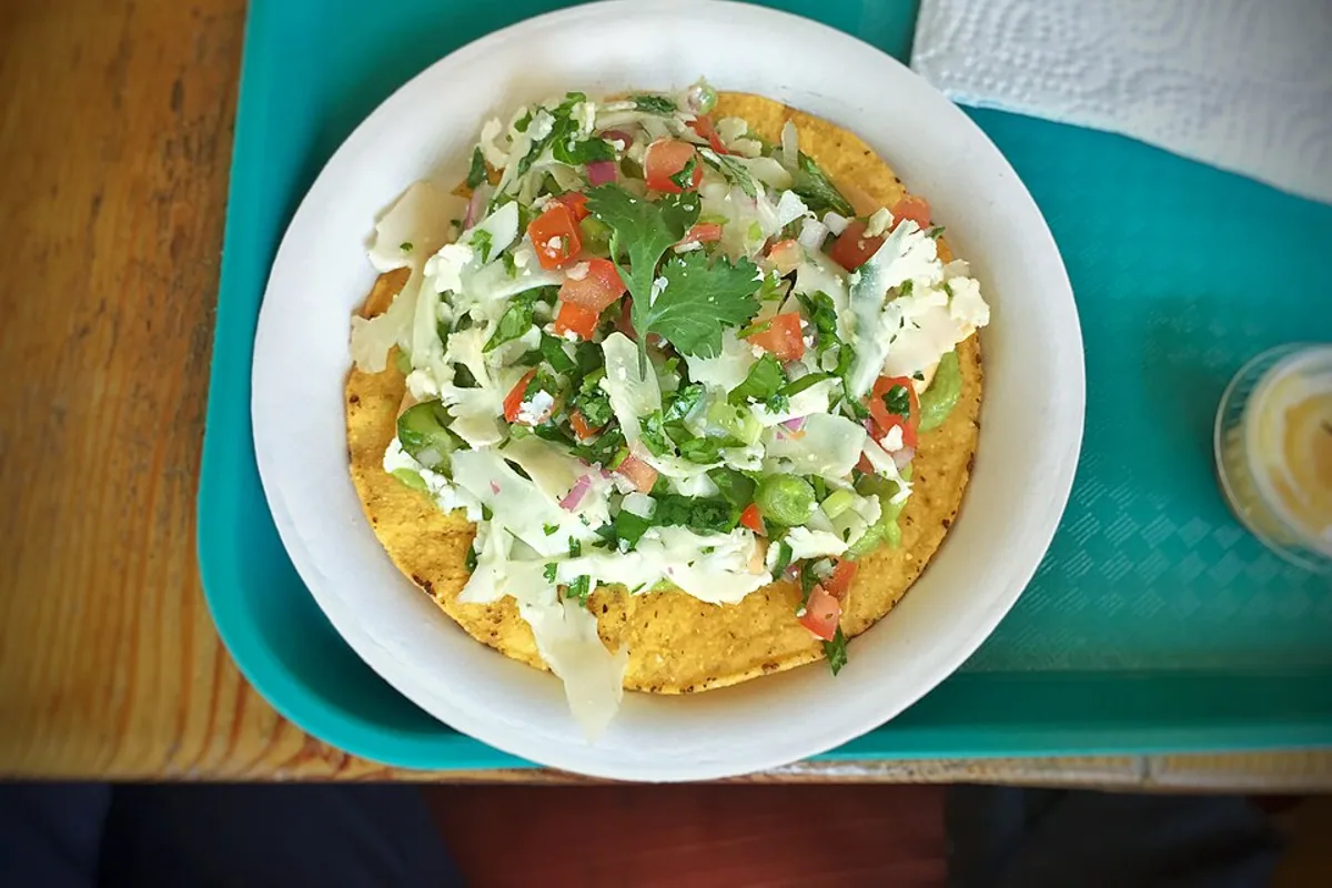 Cauliflower tostada topped with avocado tomato cilantro and creamy cashew salsa
