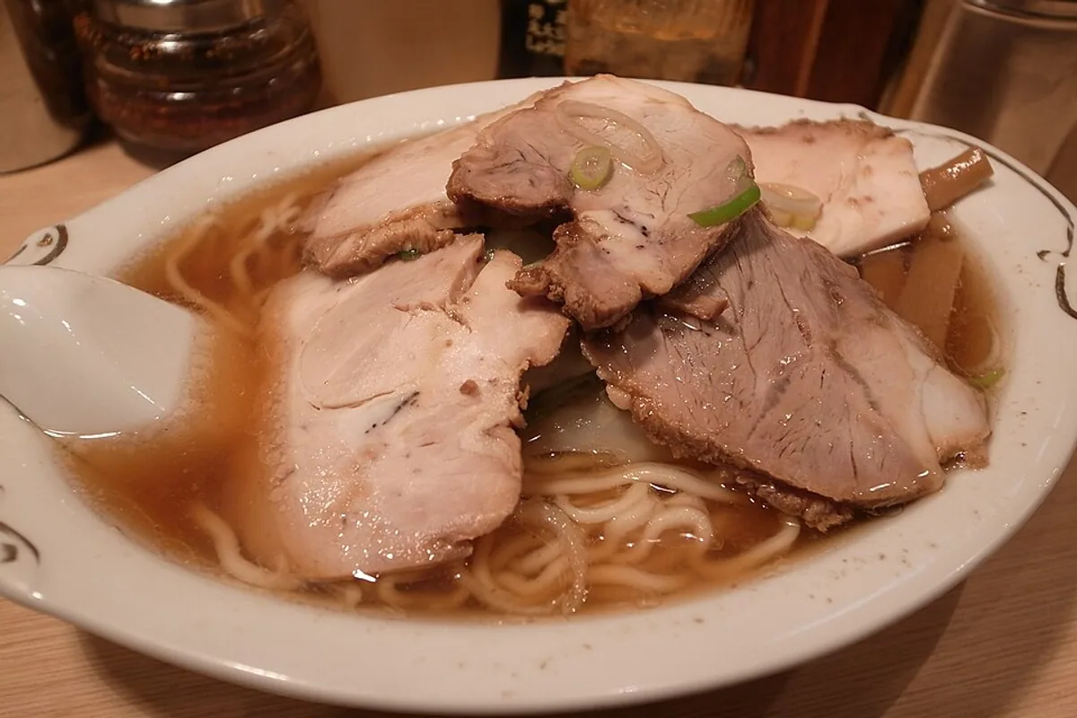 Ramen noodles in broth topped with sliced roasted chashu pork and scallions