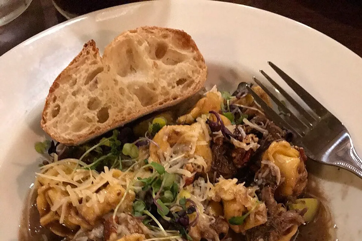 Cheese tortellini with braised beef zucchini microgreens Parmesan and bread