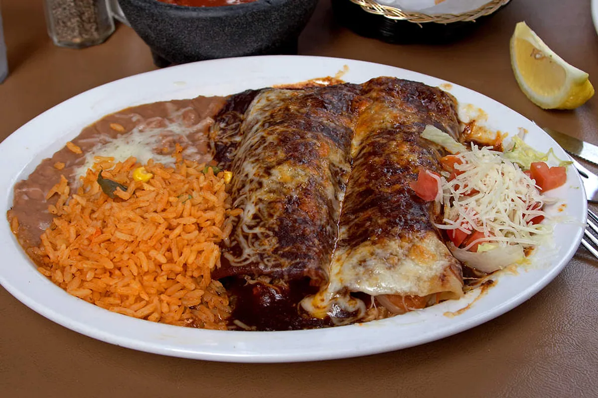 Chicken enchiladas served with Mexican rice and beans