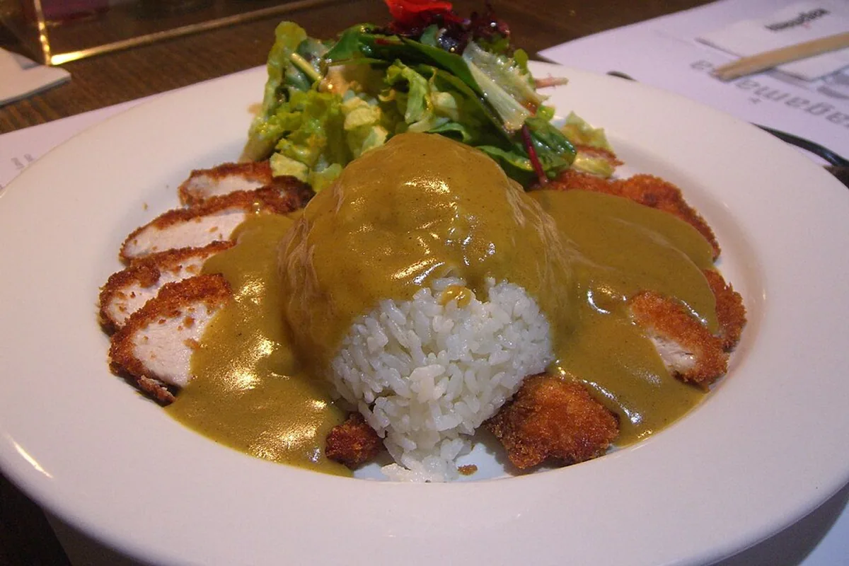 Sliced crispy chicken katsu with Japanese curry sauce steamed rice and greens
