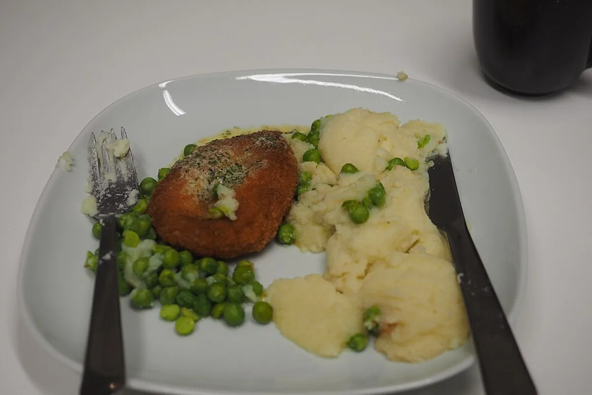 Breaded chicken Kiev with mashed potatoes peas and broccoli