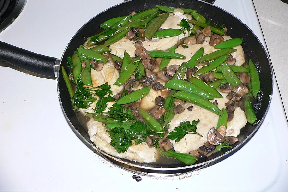 Chicken Marsala with sliced mushrooms snap peas parsley and brown pan sauce