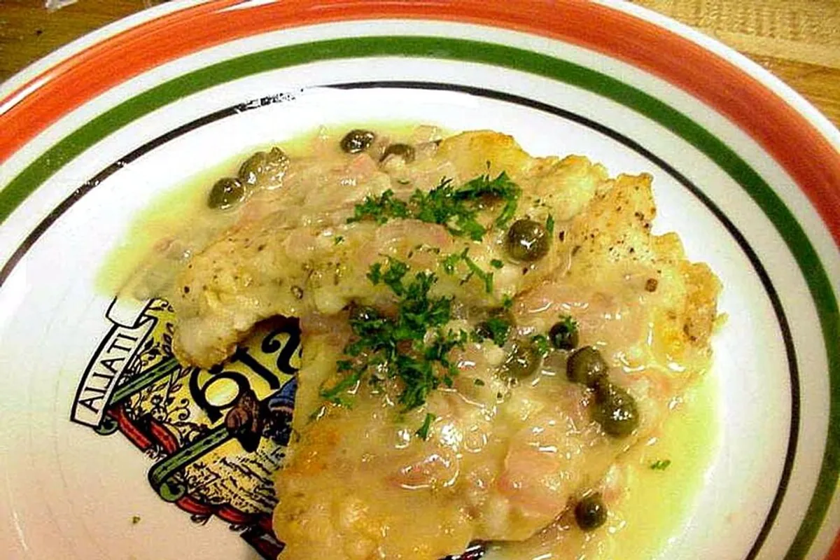 Golden chicken piccata cutlet with lemon butter sauce capers and parsley