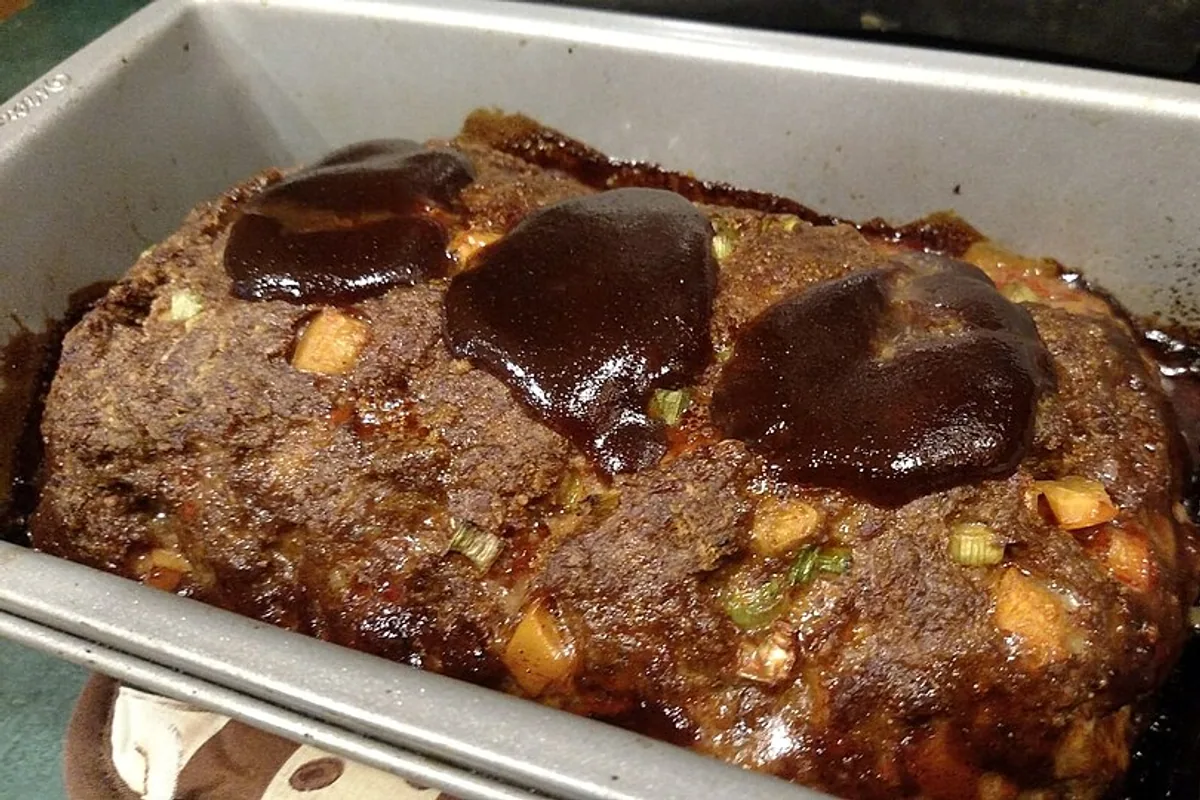Sliced stuffed beef meatloaf with a browned tomato-glazed top