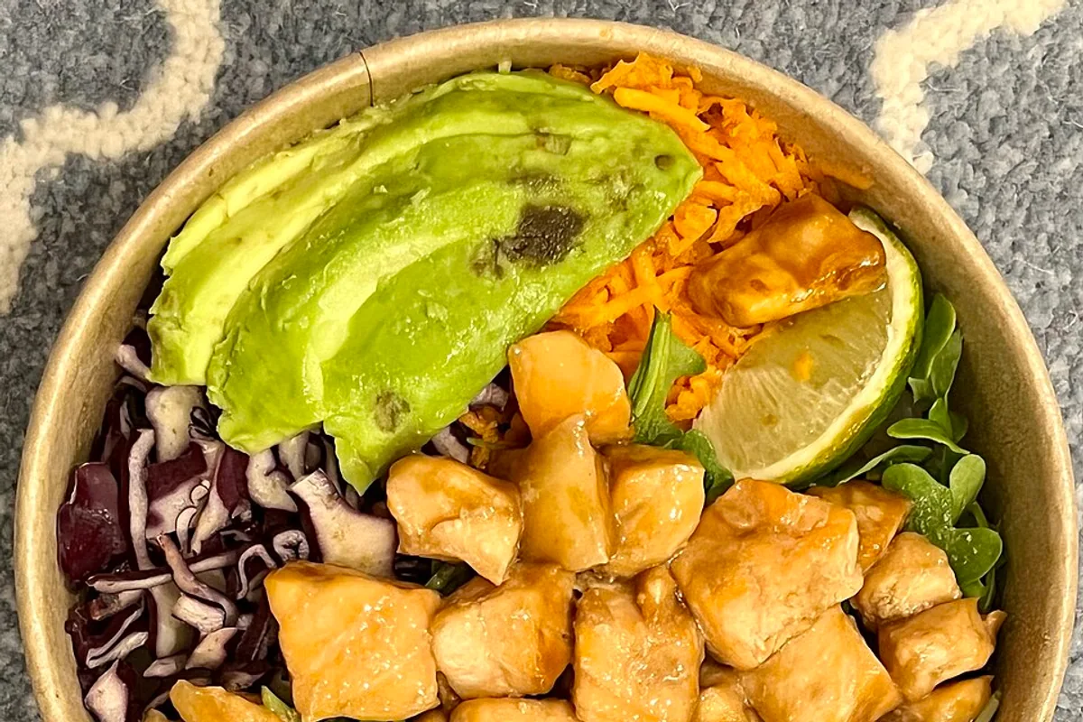 Cooked salmon poke bowl with avocado rice mango cabbage and lime