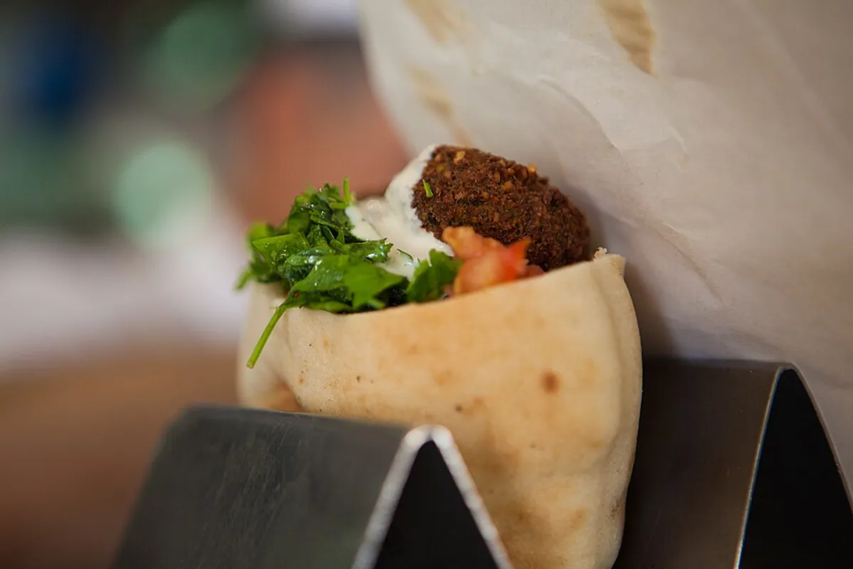 Falafel tucked into pita with tomato cucumber greens and herbs