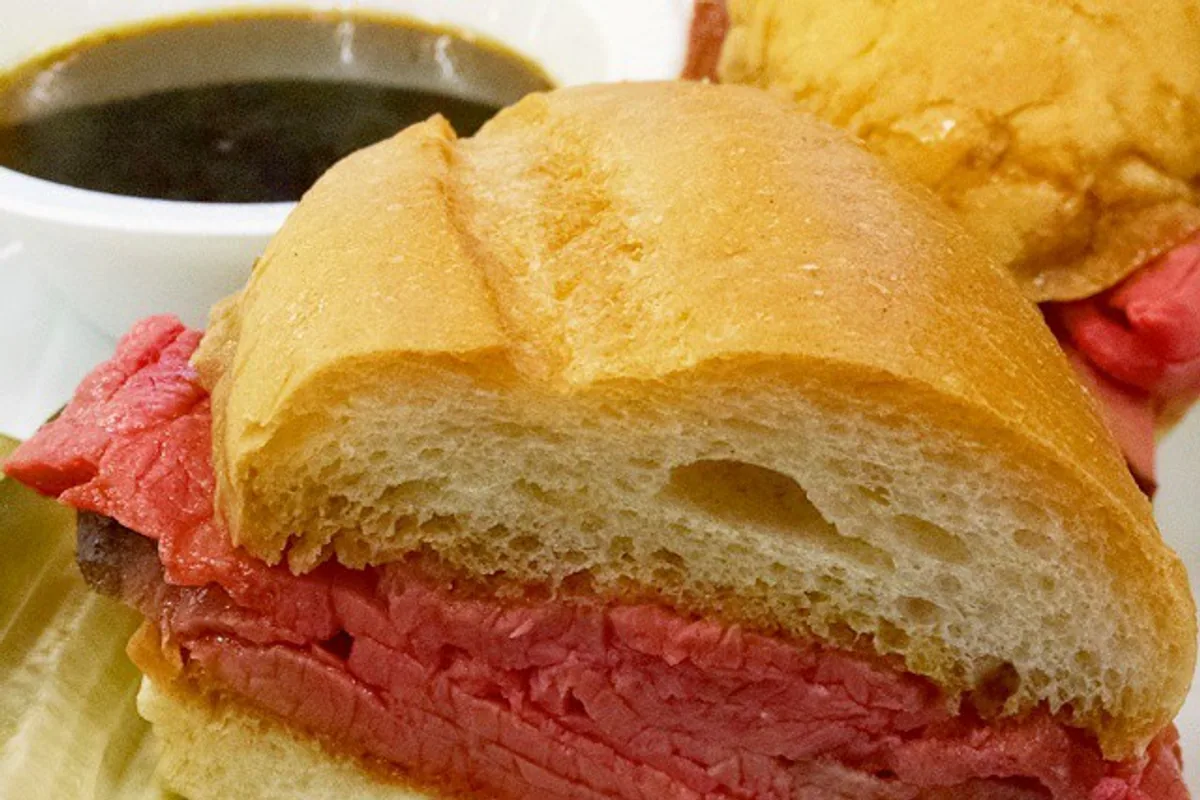 Rare roast beef French dip sandwich with au jus chips and pickle