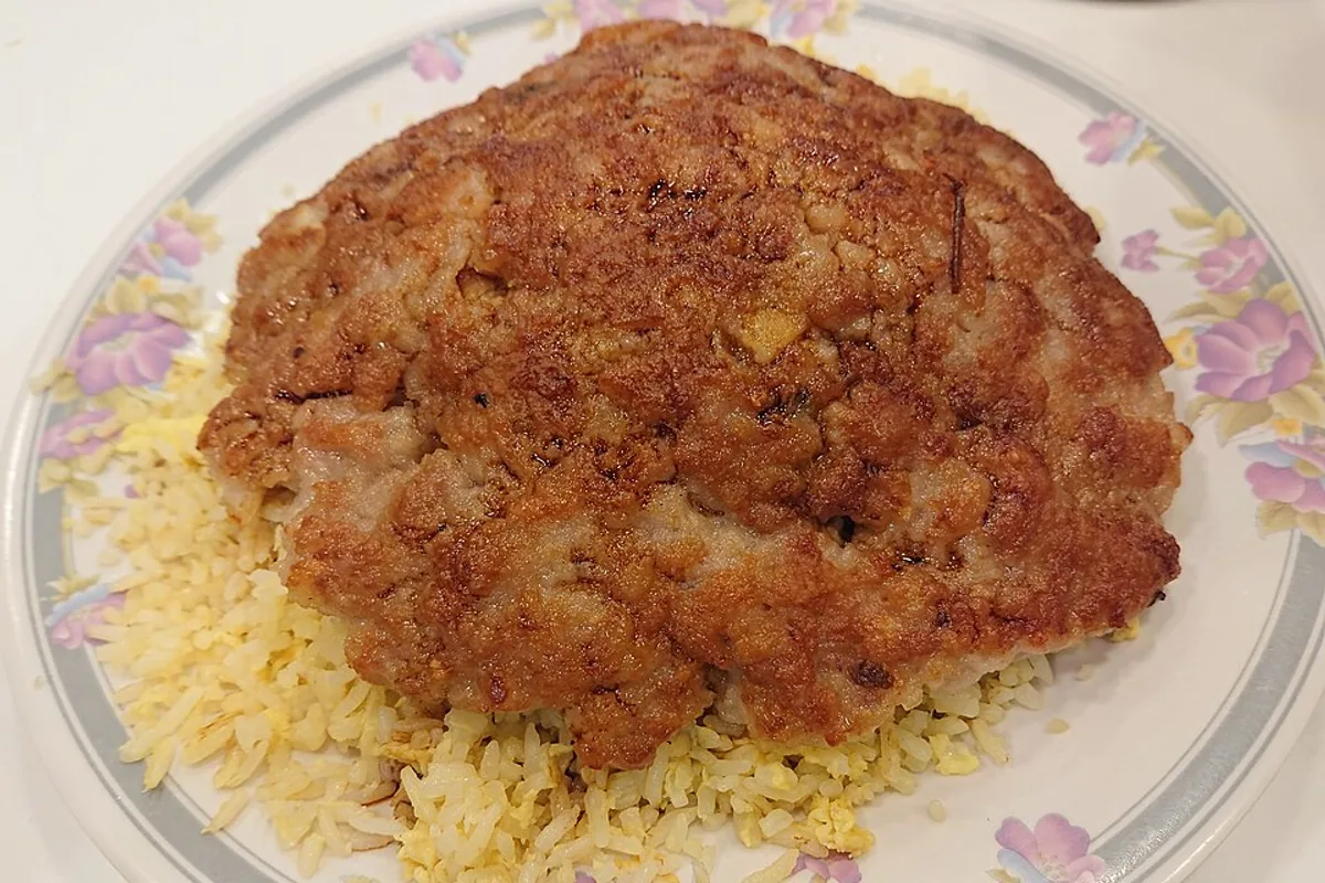 Large browned pork patty served over seasoned fried rice