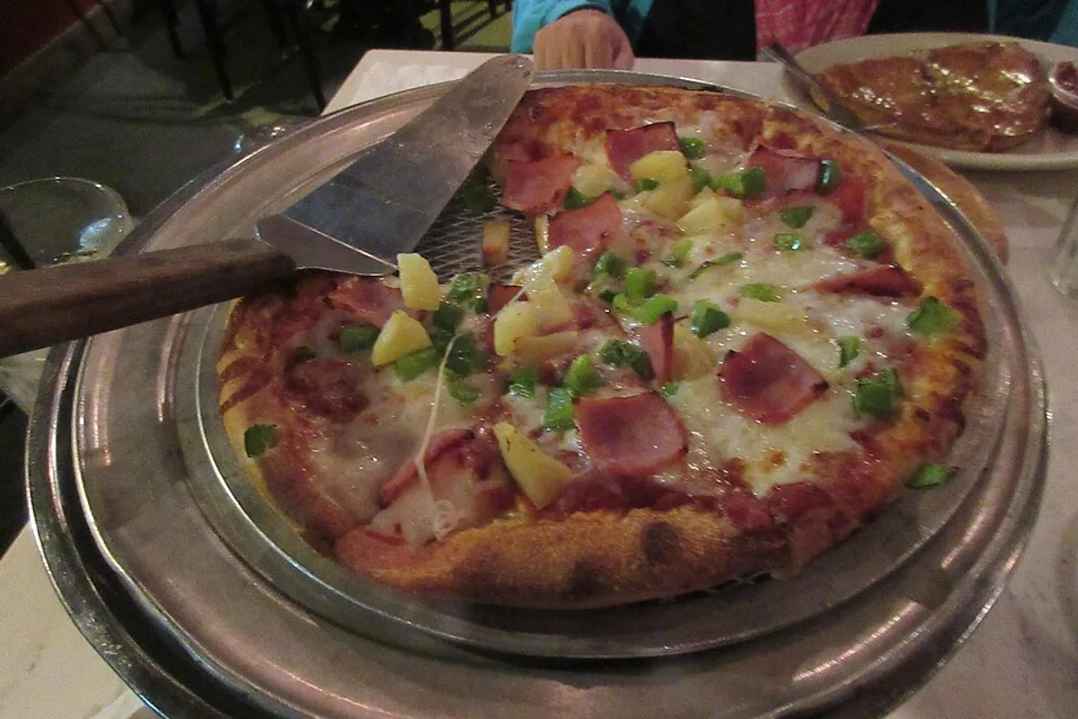 Hawaiian pizza with ham pineapple green pepper tomato sauce and cheese