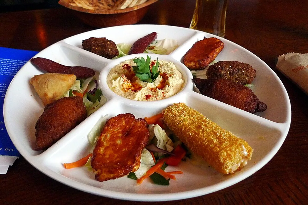 Mezze platter with hummus falafel samosas vegetables and assorted fried bites