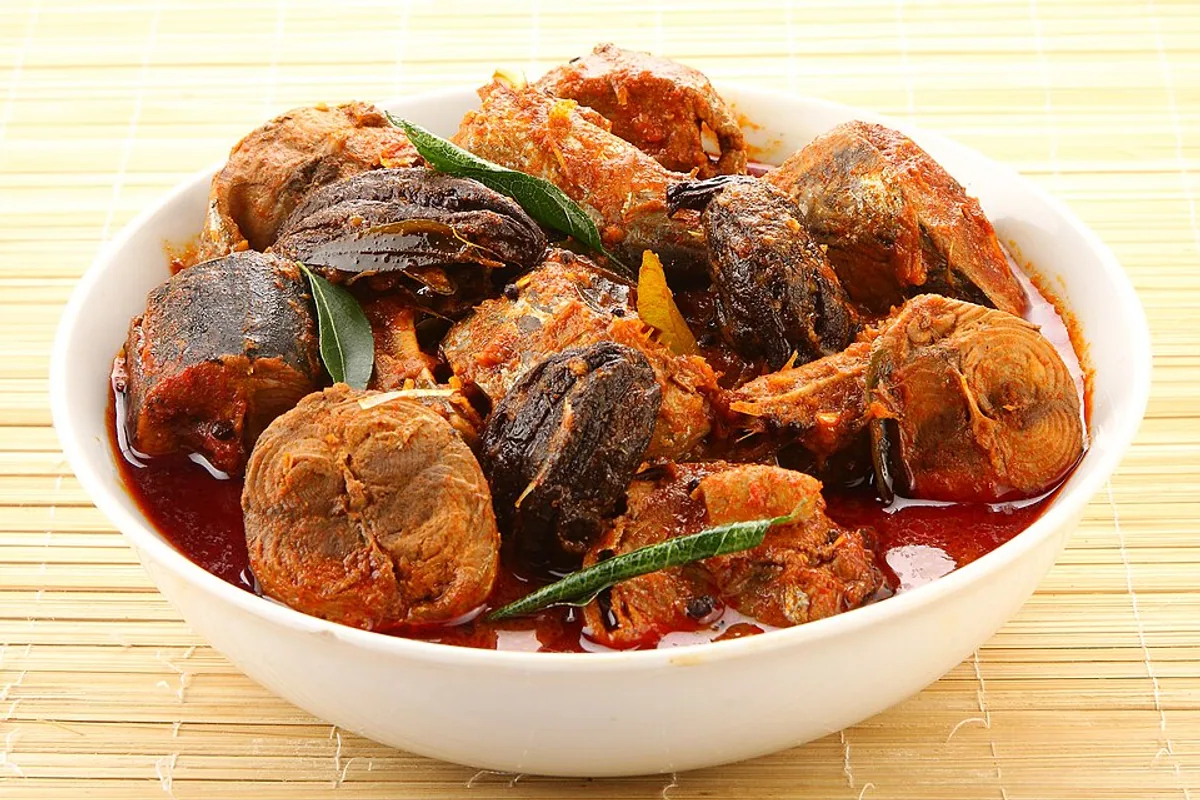 Kerala fish curry with fish pieces red coconut sauce and curry leaves
