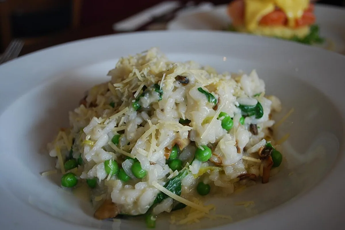 Creamy risotto with leeks mushrooms peas spinach herbs and Parmesan