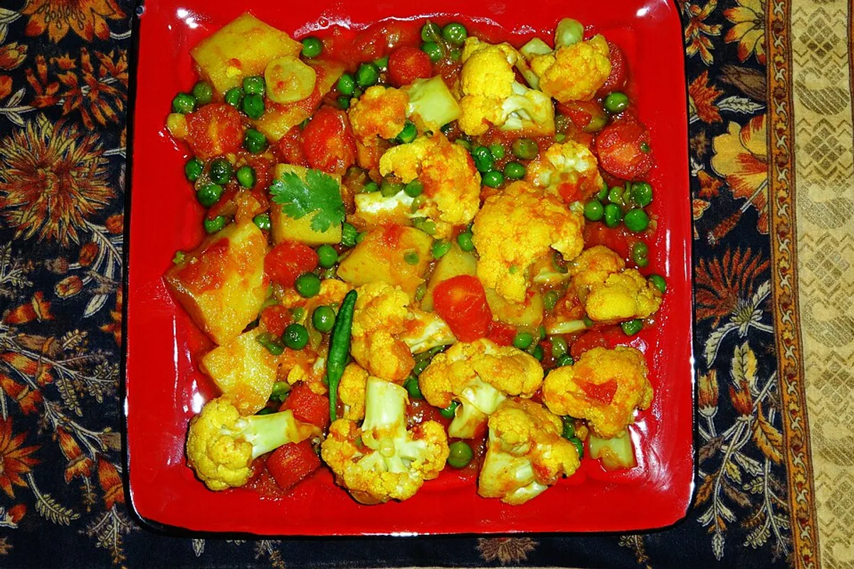 Mixed vegetable curry with cauliflower potatoes carrots peas tomato sauce and herbs