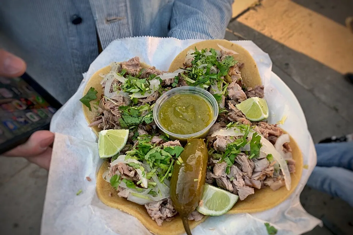 Crispy pork shoulder tacos with onion cilantro avocado and lime