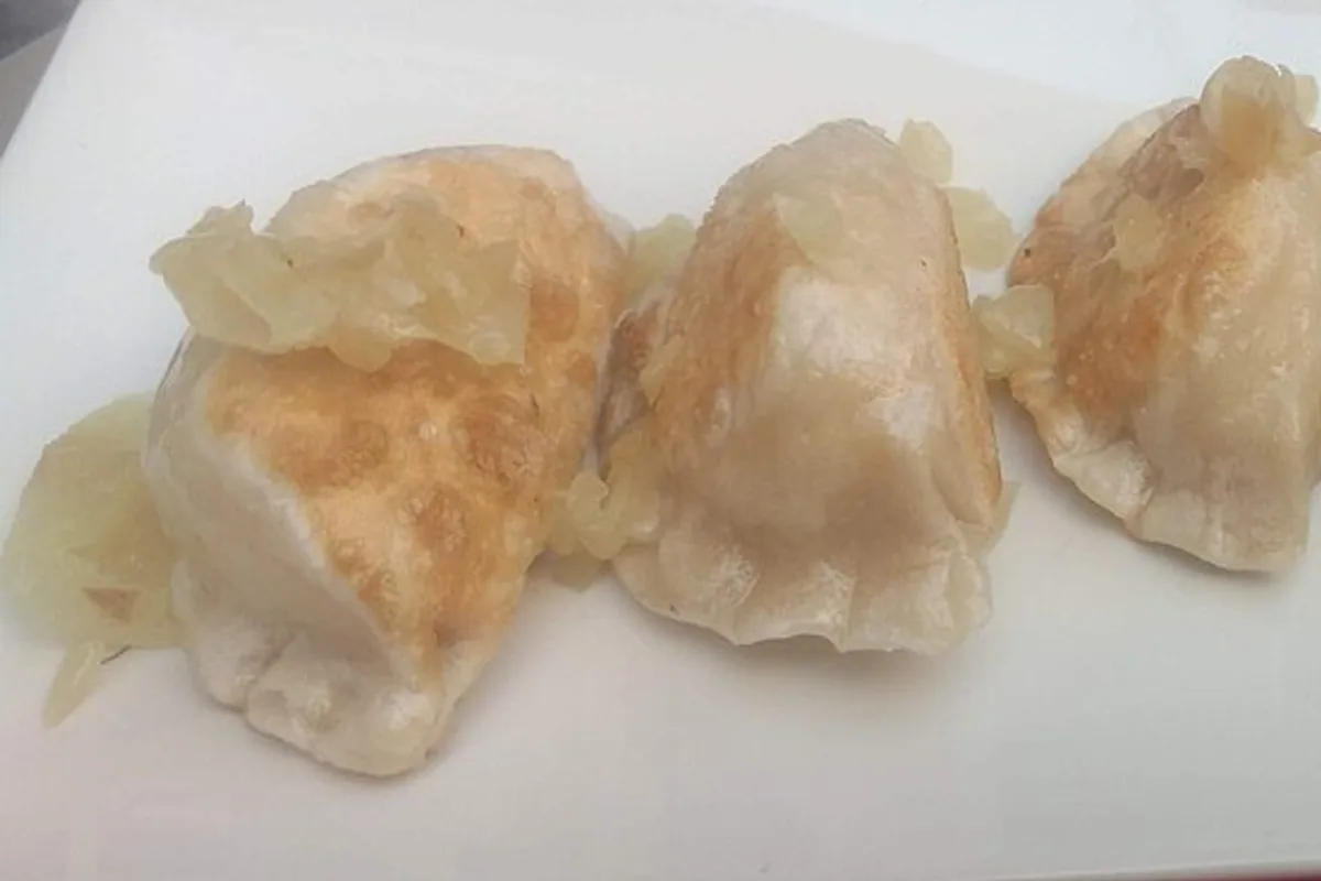 Pan-fried potato and cheese pierogi topped with soft onions