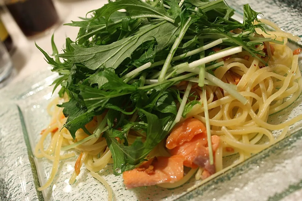 Salmon pieces with long pasta mizuna greens and light broth