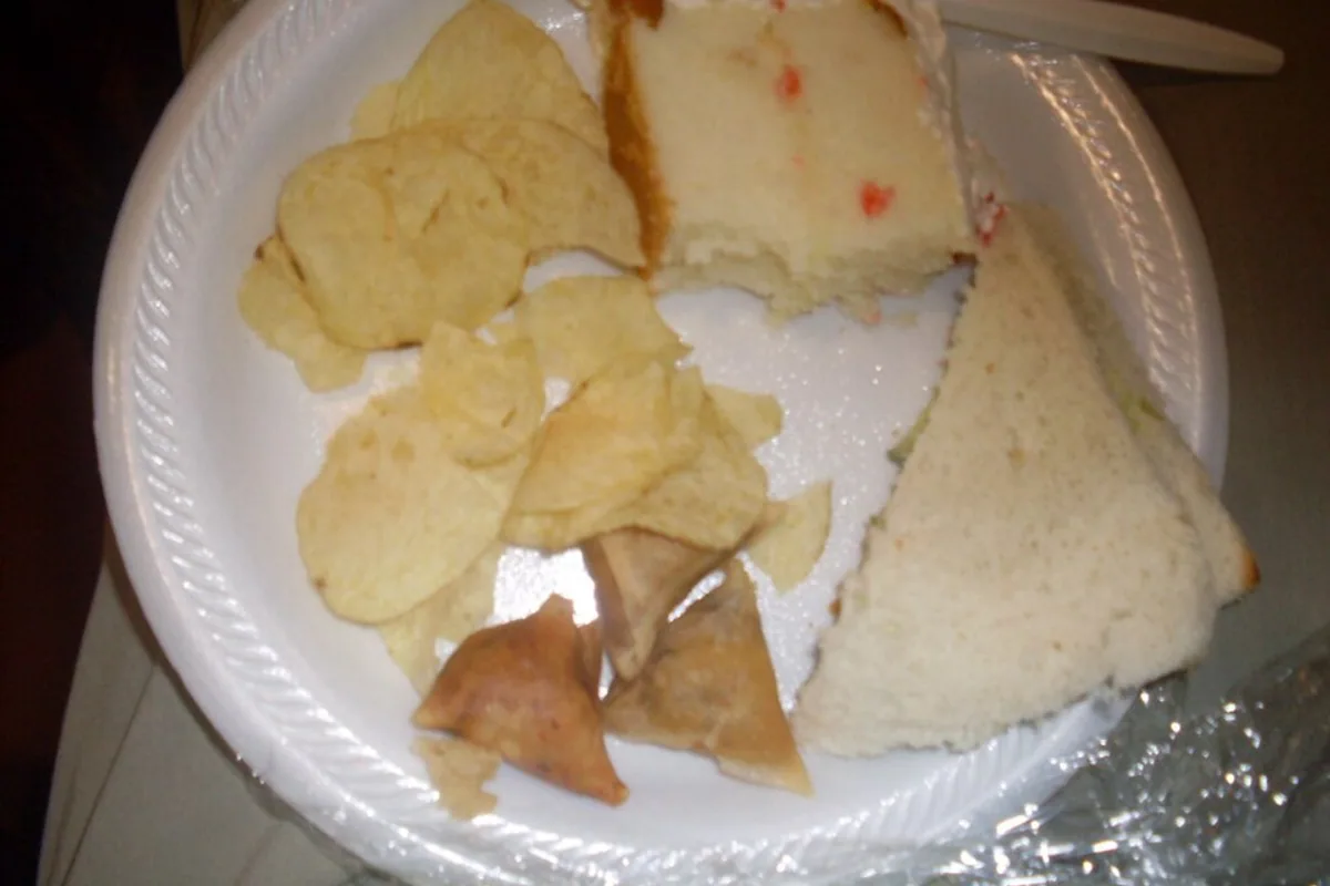 Plate with cucumber sandwiches vegetable samosas potato chips and cake