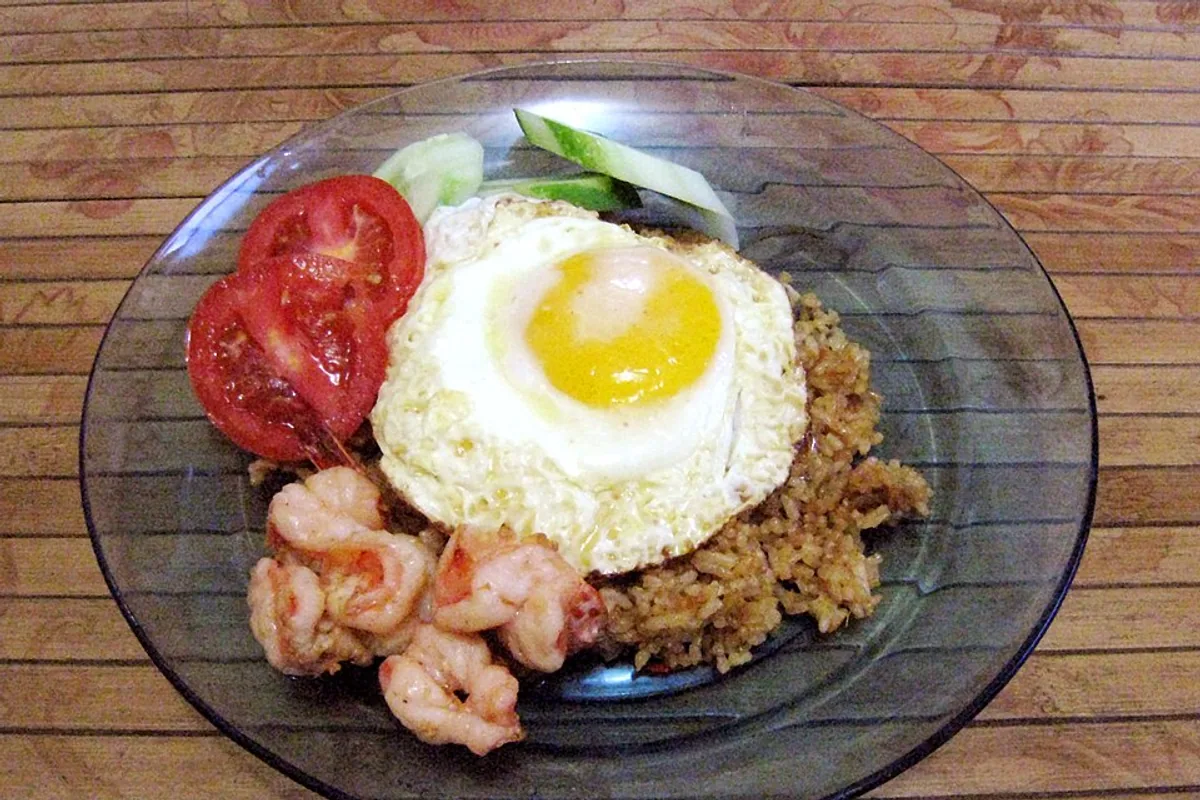 Shrimp nasi goreng with fried egg cucumber tomato and crackers