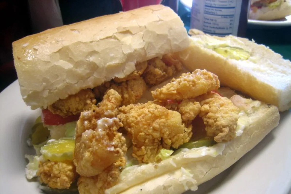 Open shrimp po boy sandwich filled with crisp shrimp beside fries