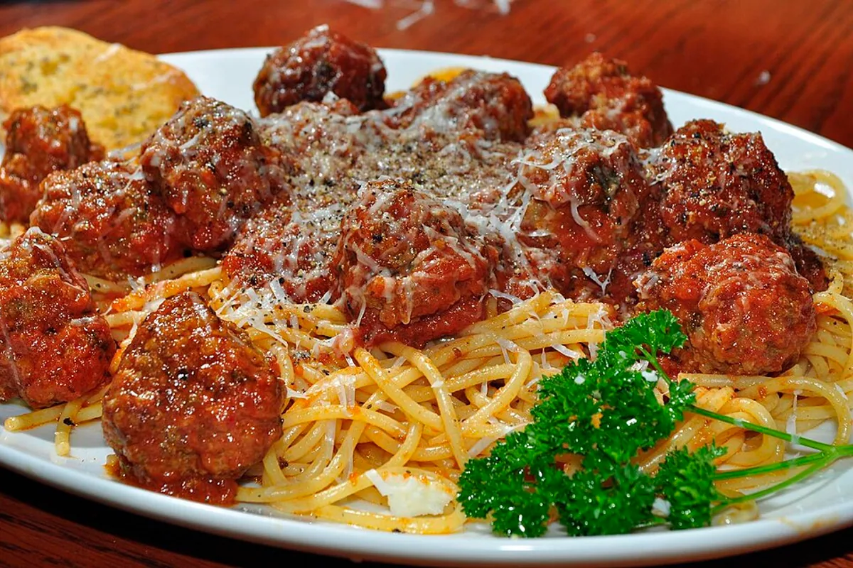 Spaghetti in tomato sauce topped with beef meatballs and grated cheese