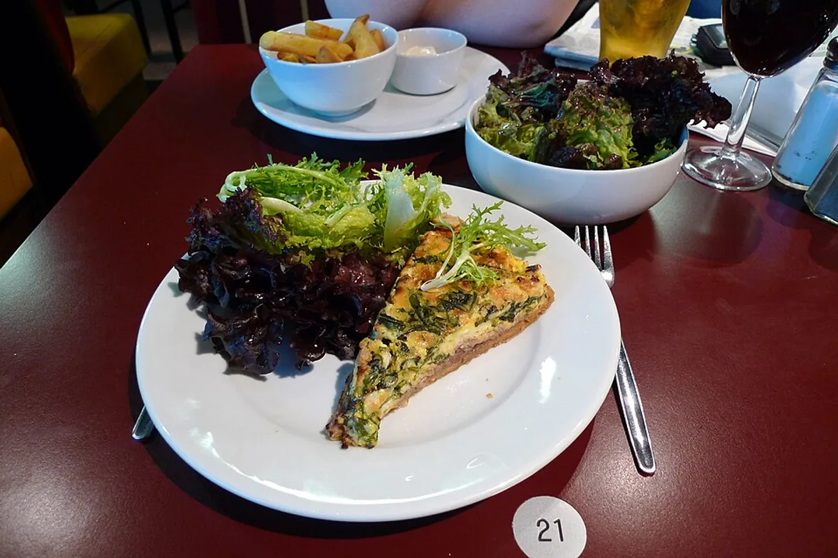 Spinach pie wedge with leafy salad and a dark bean side