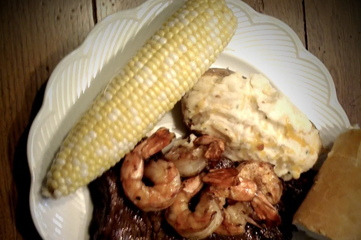 Stuffed baked potato served with sauteed mushrooms corn and bread
