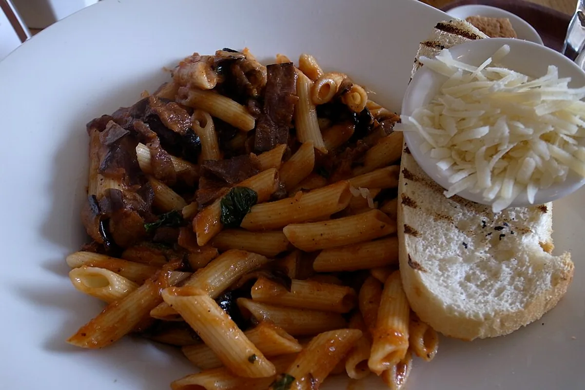 Tomato-sauced penne with mushrooms herbs and garlic bread