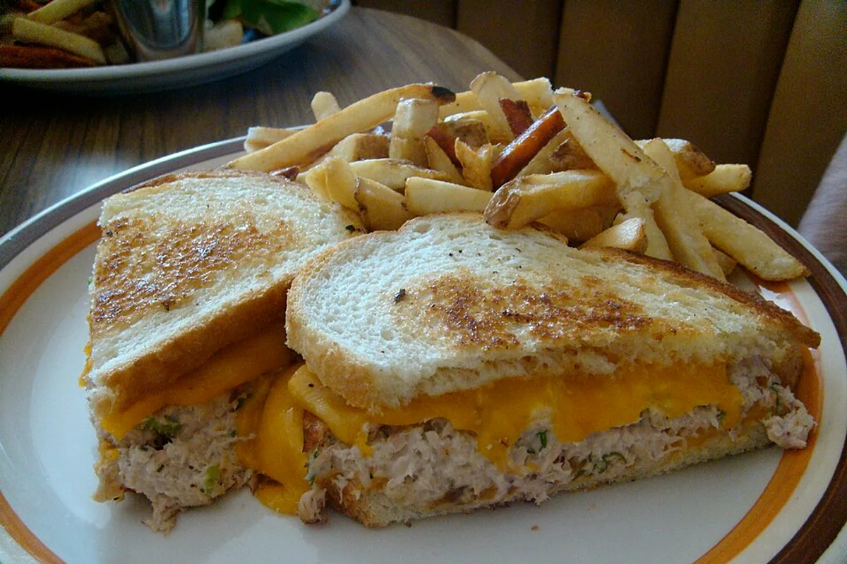 Griddled tuna melt sandwich halves with melted cheddar and French fries