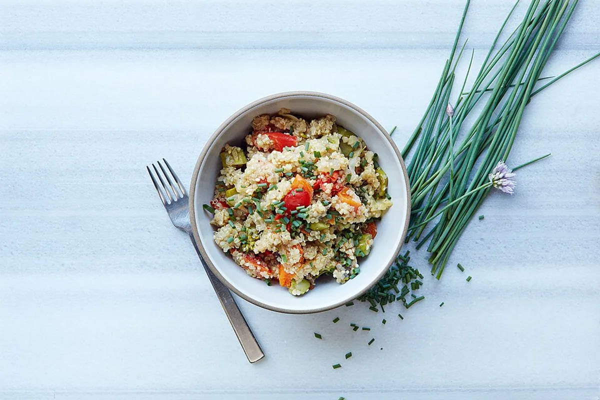 Quinoa bowl with red and yellow peppers cucumber tomato and fresh chives